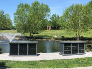 Cremation garden with a pond behind two 9-niche community columbaria set on a concrete pathway. 