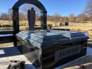 Custom granite mausoleum with an angle standing under a granite arch on a concrete foundation.