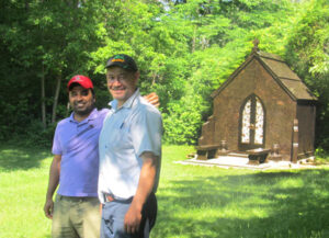 Salem Stones' CEO & Sales Director stand in front of custom granite mausoleum with benches leading to bronze doors.