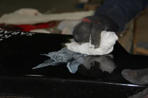 Adding white pigment to laser etched angel on Jet Black granite