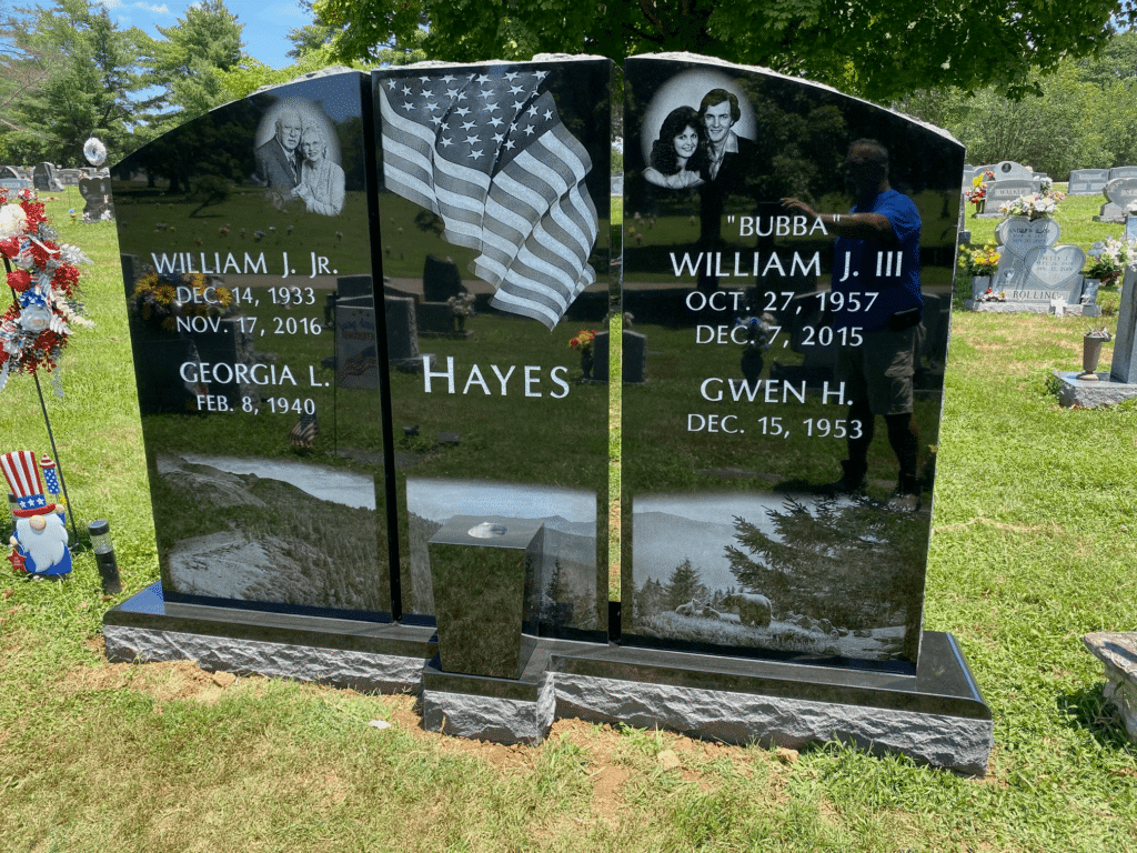 Jet black multi piece memorial with laser etchings of a flag, Mountain sceen featuring bears, and two images of a couple in their prime and later in life.